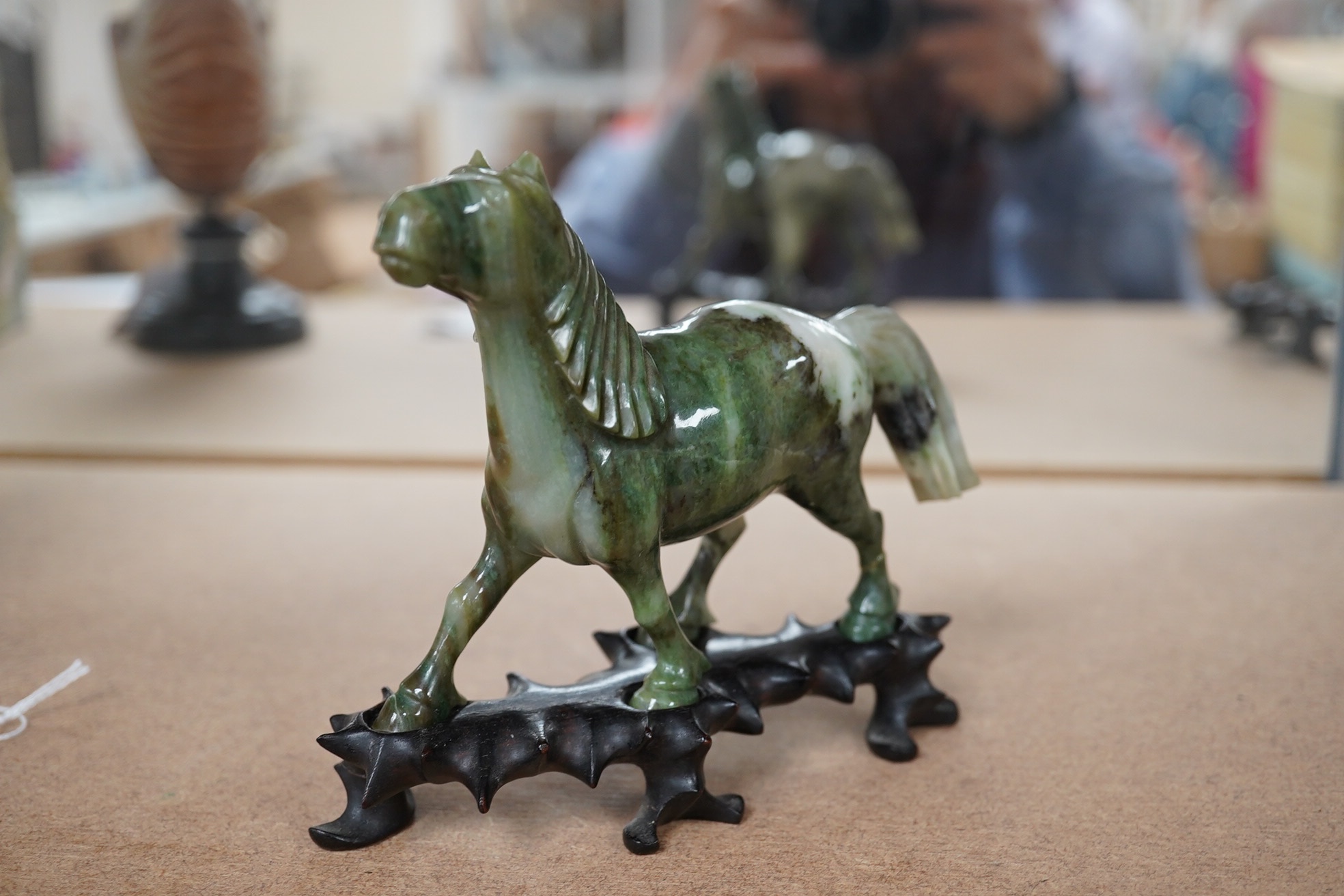 A pair of mid 20th century Chinese jadeite figures of horses, raised on hardwood stands, 13cm wide. Condition - fair, two legs broken and re-glued